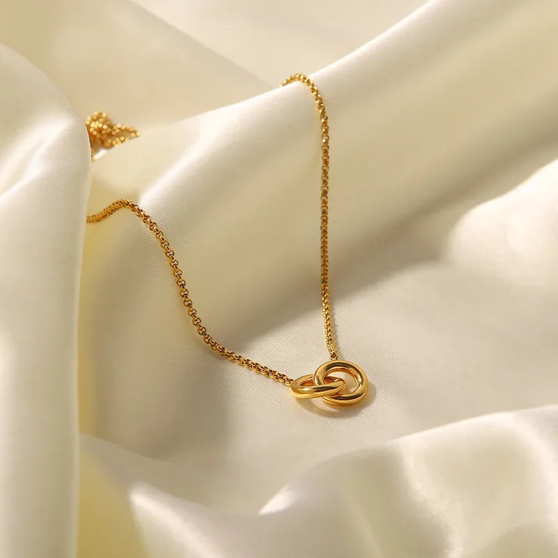 Interlinked rings gold necklace draped on white silk — 18K gold electroplated titanium pendant necklace