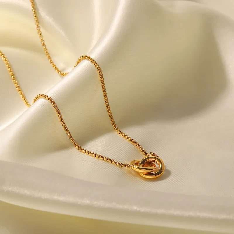 Close-up of interlinked rings pendant on gold rolo chain against white silk — non-tarnish necklace South Africa